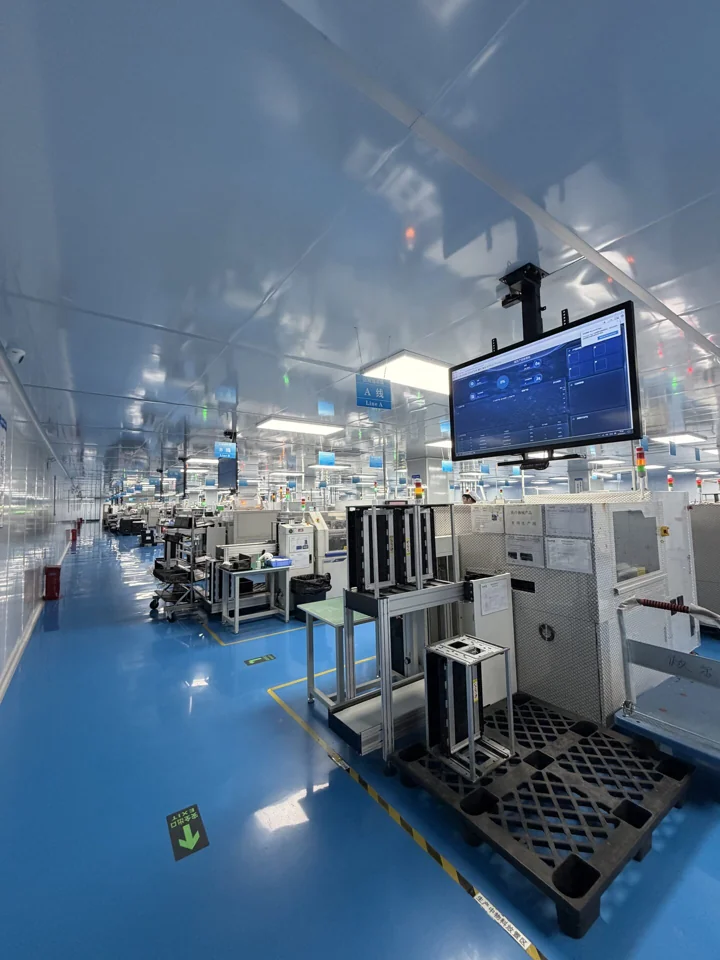 Assembly equipment along an aisle beneath an overhead display at the Shenzhen PCBA factory